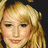 Pixelated close-up of a person with light brown hair and fair skin, showing eyes, nose, mouth, and part of the forehead against dark background.