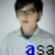 A person with short dark hair and glasses wears a light gray shirt against a plain background, with the text 'asa' displayed below.
