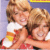 Static 50x50 pixel icon showing two cartoon-style characters with light brown hair embracing, one in white shirt and red shorts, the other in red top and white bottom, against a purple background with yellow border element.