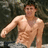 A pixelated image of a shirtless person with visible abdominal muscles standing outdoors next to a blue background with pixelated text.