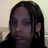 Static pixelated image of a person with long dark hair, dark clothing, and visible ear, against a light background.