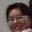 Pixelated image of a person with dark hair and a light-colored background, alongside a stylized 'Gm' text logo on a gradient backdrop.