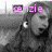 A grayscale image of a person with dark hair and beard, wearing a hooded garment, overlaid with pink text that changes from 'kenzie' to '+3'.