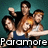 Pixelated image of five people in a group pose with one person holding a glowing object, set against a teal background with 'Paramore' text at the bottom.