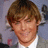 Pixelated static image of a person with light brown hair, closed eyes, and a slight smile wearing a white shirt against a blurred background.