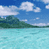 Pixelated landscape showing turquoise water, green landmasses under a blue sky with white clouds.