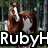 Pixelated image of a person with brown hair holding a silver microphone against a blurred background with visible text "RubyH" at the bottom.