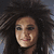A pixelated image of a person with voluminous curly hair, split into four quadrants with text overlays on black and gray backgrounds.