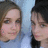 Two people in a close-up portrait with light blue background, one wearing dark clothing on the right side.