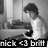 Black-and-white pixelated image of a person with dark hair wearing a light shirt, seated at a desk with a computer monitor and keyboard.