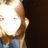 Pixelated close-up of a person with light skin, brown hair, and blue clothing against dark background.
