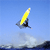 Pixelated static icon of a yellow surfboard with dark base against blue sky and water background.