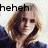 Pixelated image of a person with light brown hair wearing dark clothing, smiling while holding an object near their face, with black text reading 'heheh' in the top-left corner.