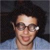 Six show a person wearing round glasses with white earpieces, making varied facial expressions including smiling, tongue-out, and pout; bottom-left displays pink text on black background