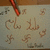 A static pixelated image shows a red pen-like object above a light gray surface with scattered brown pixel clusters resembling handwritten text or symbols.