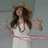 A pixelated figure in a white dress with pink accents stands against a muted gray background, arms raised in a celebratory pose.