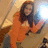 A pixelated image of a person in an orange top and gray pants holding a camera flash, next to pink text reading "This is why I'm HOT!" with star symbols.