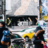 Pixelated static image showing indistinct figures and objects in a blurred urban scene with muted colors.