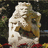 Pixelated image of a light-colored, textured object with red accents against dark background and red text reading 'Monarch Dancer <3'.