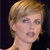 Pixelated close-up of a person with short light brown hair, neutral expression, and visible neck against dark background.