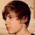 Pixelated profile view of a person with short dark brown hair, light skin, and a neutral expression against a beige background.