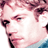 Pixelated static image of a person's face with pink and purple tones, cropped to show partial facial features against a white background.