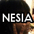 Pixelated image with large white text 'NESIA' over a dark background, featuring partial visible face and brown clothing.