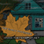 Static 50x50 pixel icon showing a large orange leaf in front of a teal house with dark windows and green grass, rendered in low-resolution pixel art style.