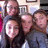 A static pixelated image shows five people in a group pose with blurred faces, wearing dark and light clothing against an indistinct background.