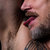 Pixelated close-up of a person's face with dark hair, pink lips, and visible neck, set against a blurred background.