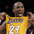 A person holds a yellow basketball jersey with 'LAKERS' and '24' text, displaying it against a dark background with blurred lights.