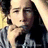 Pixelated image of a person with long dark hair wearing a checkered shirt, hand near face, next to text reading 'Curly Haired Catie!' on light background.