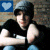 Pixelated static image of a person in dark clothing with light-colored hair, featuring a blue square icon with white heart symbol in top-left corner.