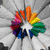 A circular rainbow-colored icon with a white star at its center, surrounded by radiating gray shapes, displayed in a