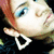 Pixelated close-up of a person's face with light skin, blue eyes, and red hair, wearing large white hoop earrings against a dark background.