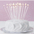 A white frosted cake with a single candle on a plate, set against a light purple background.
