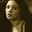 Pixelated static image of a person's face and upper torso with warm brown tones against dark background, likely from early digital art or low-resolution capture.