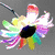 A colorful flower with rainbow petals and a black center rotates clockwise against a gray background.
