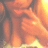 A pixelated image of a person with long hair covering their face with both hands, wearing a light-colored top, in warm orange and yellow tones.