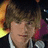 Pixelated image of a person with brown hair and dark clothing against a bright background, next to red text on a solid pink backdrop.
