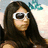A pixelated image of a person with long dark hair wearing white-framed sunglasses, set against a light background with blue and pink tones.