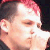 Pixelated close-up of a person's face with closed eyes, pink hair, and light skin tone against dark background.