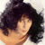 Pixelated portrait of a person with dark curly hair, light skin, and a neutral expression, cropped to show shoulders and head against a light background.