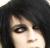Pixelated close-up of a person's face with dark hair, visible eye and nose details against a dark background.