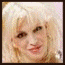 A pixelated image of a person with blonde hair wearing red clothing and holding a golden microphone, displayed in four