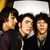 Three pixelated figures in dark clothing with light skin tones, one holding a blank white speech bubble above their head.