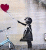 A pixelated figure in a dark dress holds a red heart-shaped balloon while standing on a light-colored background with faint blue and gray shapes.