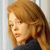 Pixelated close-up of a person with long light brown hair wearing a dark top against a light background.