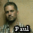 Pixelated image of a person with short dark hair wearing a checkered shirt, standing against a textured beige background with visible text reading 'Paul' in white letters on black.