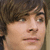 Pixelated close-up of a person's face with brown hair, light skin tone, and neutral expression against dark background.